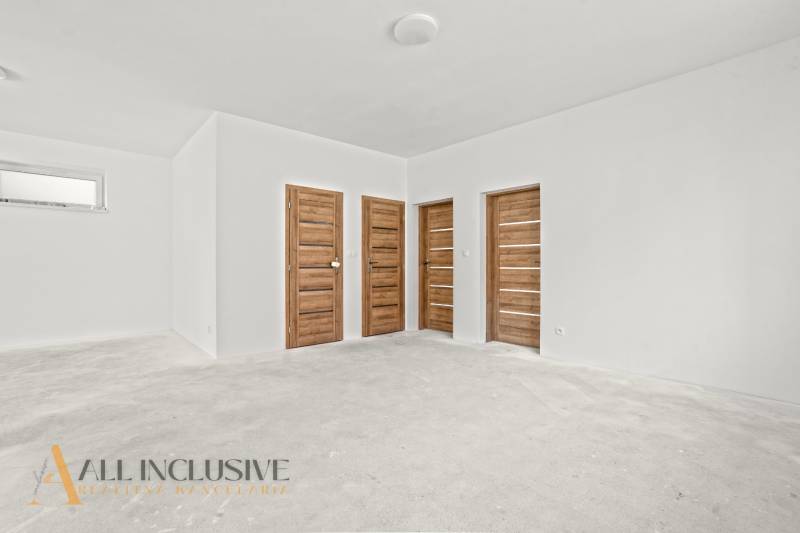 Ein geräumiger Raum in einem Einfamilienhaus mit weißen Wänden und Türen in Holzoptik.