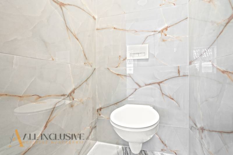 Ein Badezimmer in einem Einfamilienhaus mit luxuriösen Fliesen und einer eingebauten Toilette.