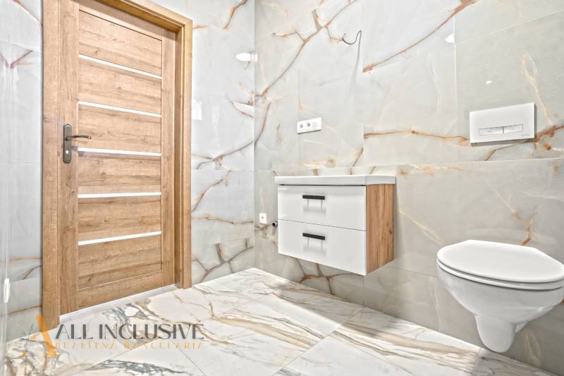 Badezimmer in einem Einfamilienhaus mit Fliesen und Bodenbelag in Marmoroptik.