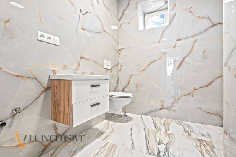 Badezimmer in einem Einfamilienhaus mit Keramikfliesen und Möbeln in Holzoptik.