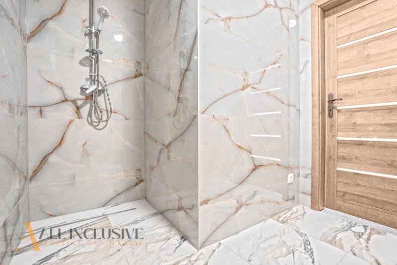 Badezimmer im Einfamilienhaus mit Marmorimitat an den Wänden und Holztüren.
