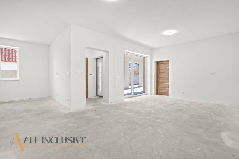 Geräumiges Interieur eines Einfamilienhauses mit weißen Wänden und Fliesenboden.