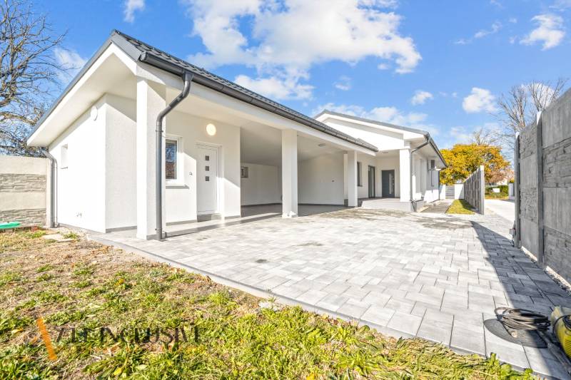 Ein Einfamilienhaus in Orechová Potôň mit weißer Fassade und gepflastertem Eingang.