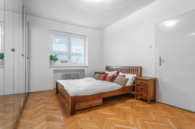 Schlafzimmer in einer 3-Zimmer-Wohnung mit Holzmöbeln und einem Boden mit Holzdekor.
