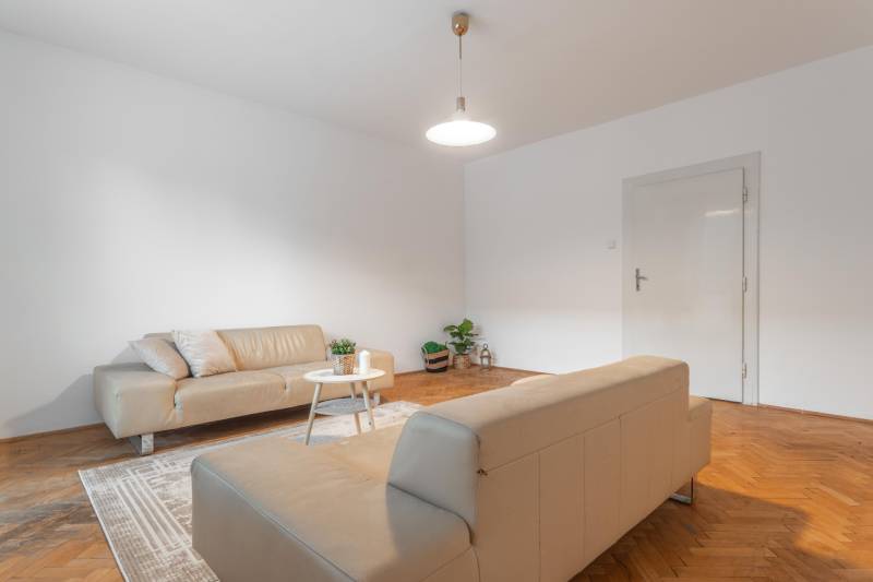 Wohnzimmer in einer 3-Zimmer-Wohnung mit Sofas und Holzboden.
