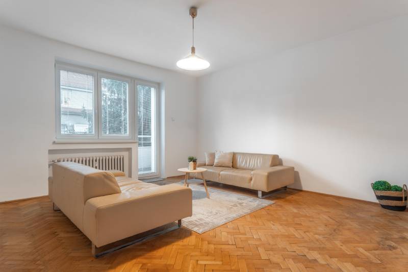 Wohnzimmer in einer 3-Zimmer-Wohnung mit beigen Sofas und einem Boden in Holzoptik.