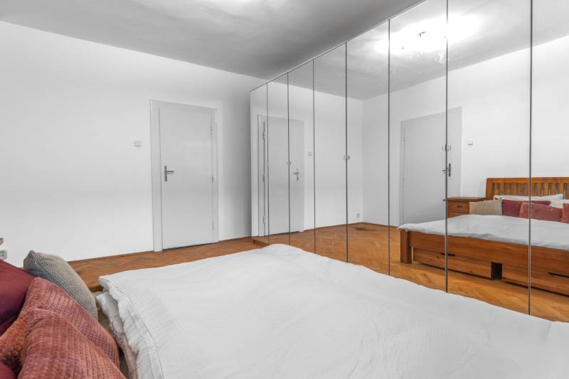Schlafzimmer in einer 3-Zimmer-Wohnung mit Holzboden, Spiegelschränken und Bett.
