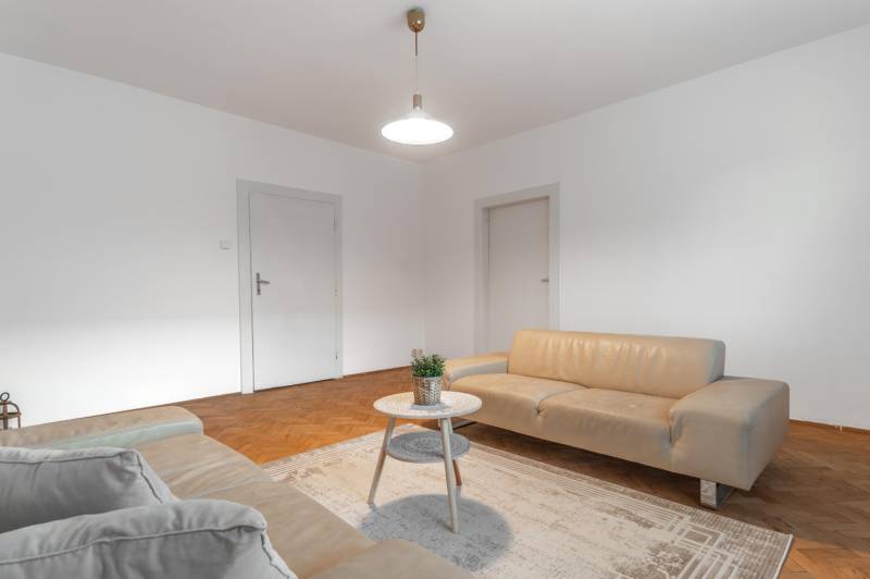 Wohnzimmer in einer 3-Zimmer-Wohnung mit hellen Sofas und einem Boden in Holzoptik.