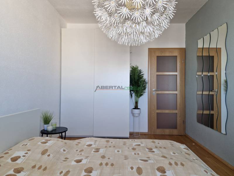 Schlafzimmer mit dekorativer Leuchte, Kleiderschrank und Holzboden in einer 3-Zimmer-Wohnung.