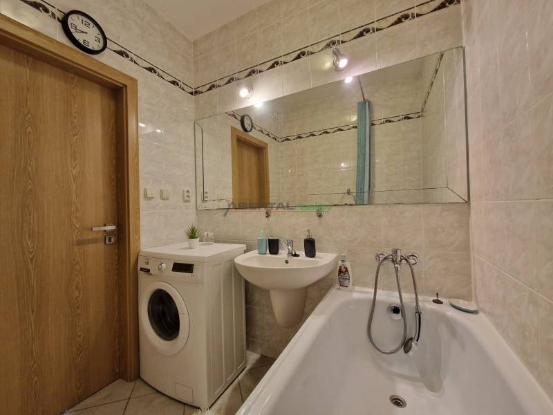 Badezimmer in einer 3-Zimmer-Wohnung mit Badewanne, Waschmaschine und großem Spiegel.