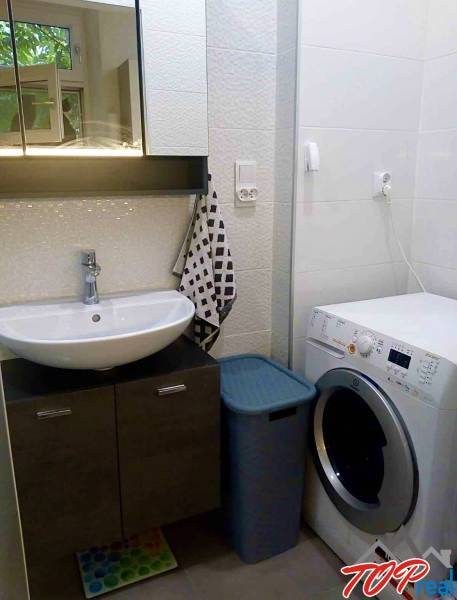 Badezimmer in einer Einzimmerwohnung mit Spiegelschrank, Waschbecken und Waschmaschine.