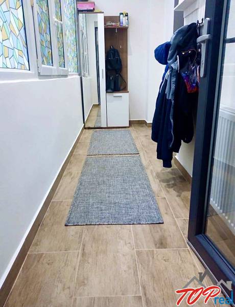 Flur mit Fliesen in Holzoptik in einer Einzimmerwohnung mit einem Einbauschrank für Kleidung.