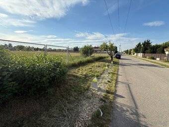 Straße in Miloslavov mit Grundstücken für Wohnbebauung und angrenzenden Grünflächen.