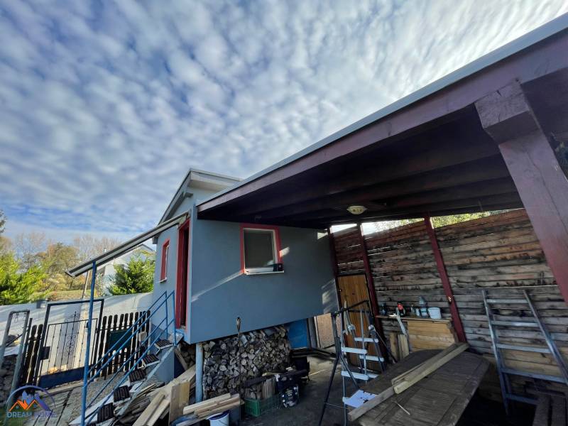 Ein Haus in Komárno in der Neusiedlung mit einer Treppe und einem hölzernen Unterstand unter den Wolken.