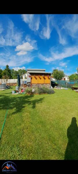 Der Garten bei der Hütte in der Neuen Siedlung in Komárno mit blauem Himmel und gepflegtem Rasen.
