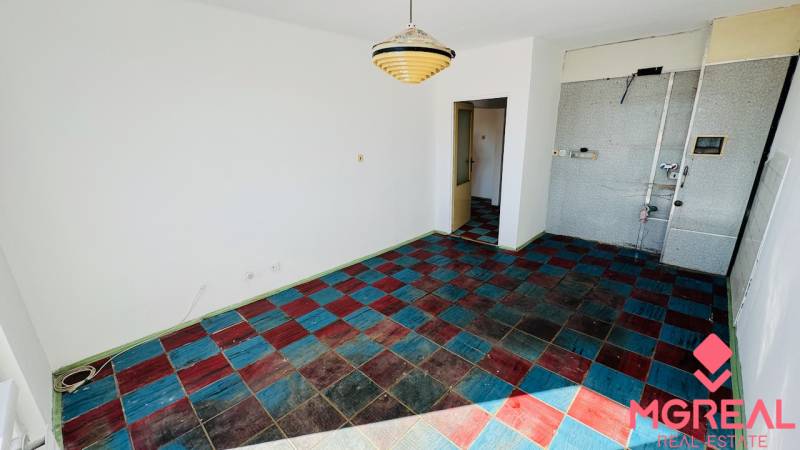 Ein Zimmer in einer Einzimmerwohnung mit einem farbigen Fliesenboden und einer Hängelampe.