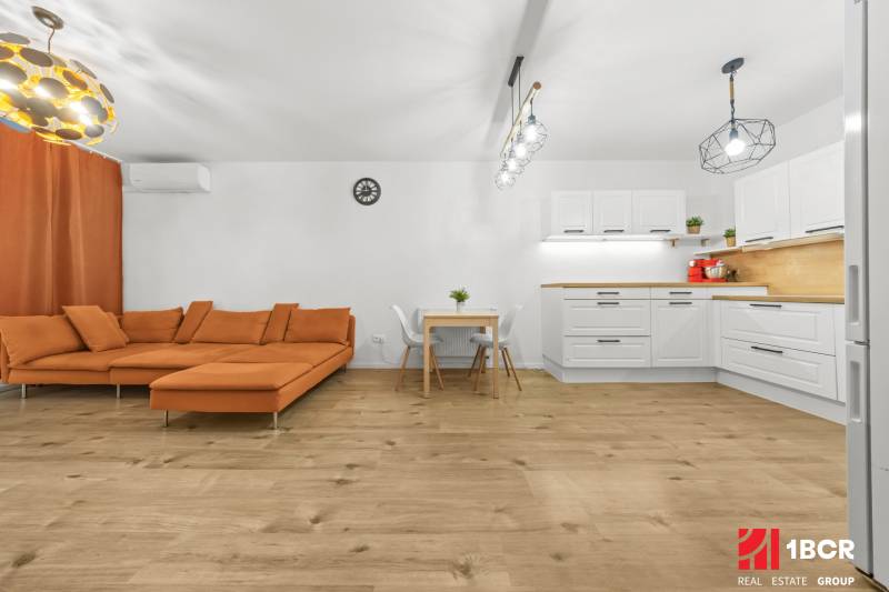 Wohnzimmer in einer 2-Zimmer-Wohnung mit einem orangefarbenen Sofa und einem Holzboden.