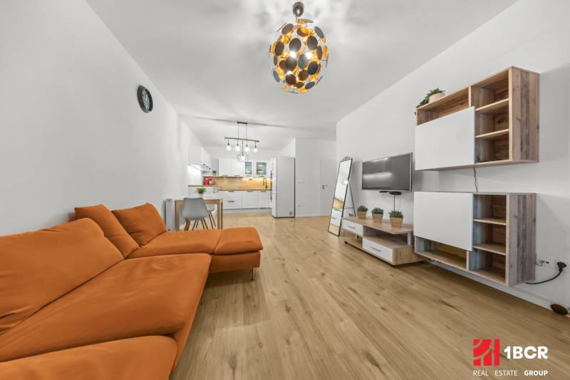 Wohnzimmer mit einem orangefarbenen Sofa und einem Boden in Holzoptik in einer Zweizimmerwohnung.
