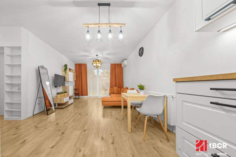 Wohnzimmer in einer 2-Zimmer-Wohnung mit Holzboden und orangenen Möbeln.