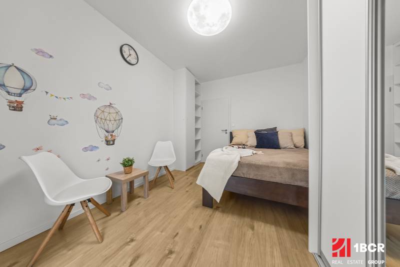 Schlafzimmer in einer 2-Zimmer-Wohnung mit Wanddekor und Holzboden.