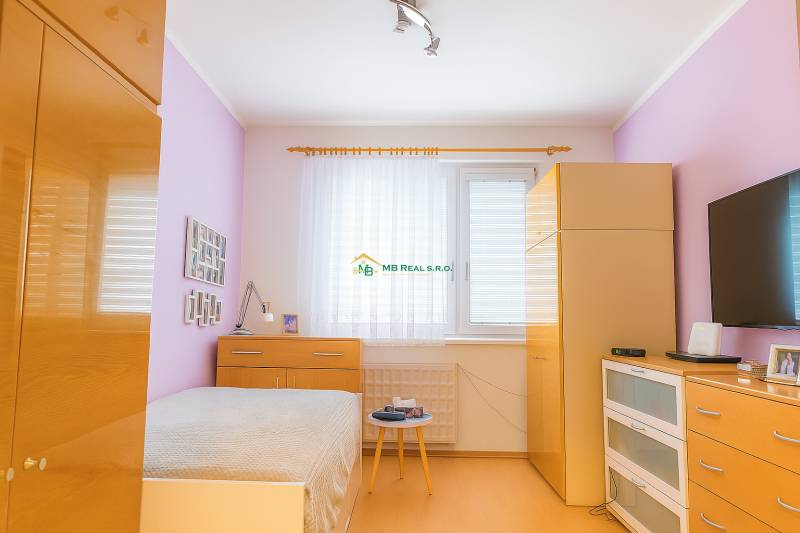 Helles Schlafzimmer in einer Zweizimmerwohnung mit einer Kommode mit Schubladen und einem Einbauschrank.