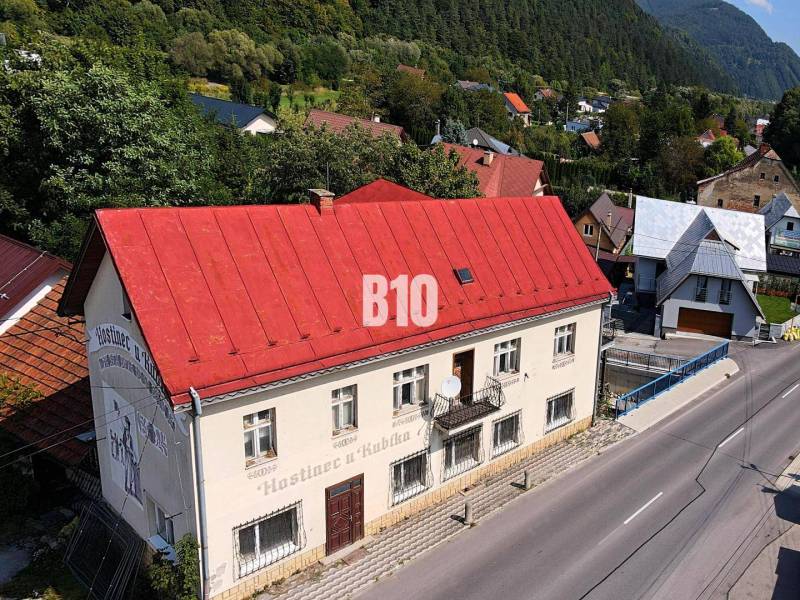 Ein Gebäude in Belej mit einem roten Dach auf der Hauptstraße, umgeben von Grün und Häusern.