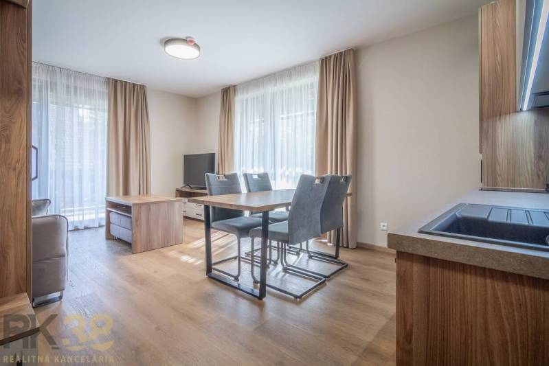 Wohnzimmer in einer 2-Zimmer-Wohnung mit Esstisch und Boden in Holzoptik.