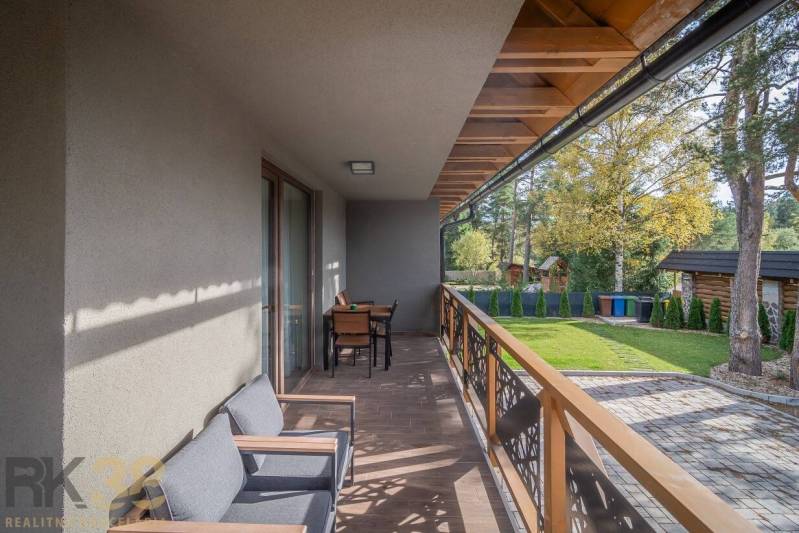 Balkon einer 2-Zimmer-Wohnung in Tatranská Lomnica mit Holzboden und Gartenmöbeln.