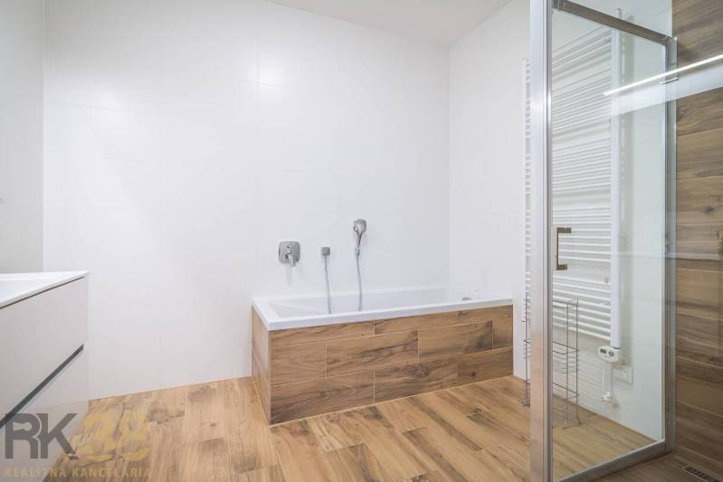 Badezimmer in einer 2-Zimmer-Wohnung mit Badewanne und Boden in Holzoptik.