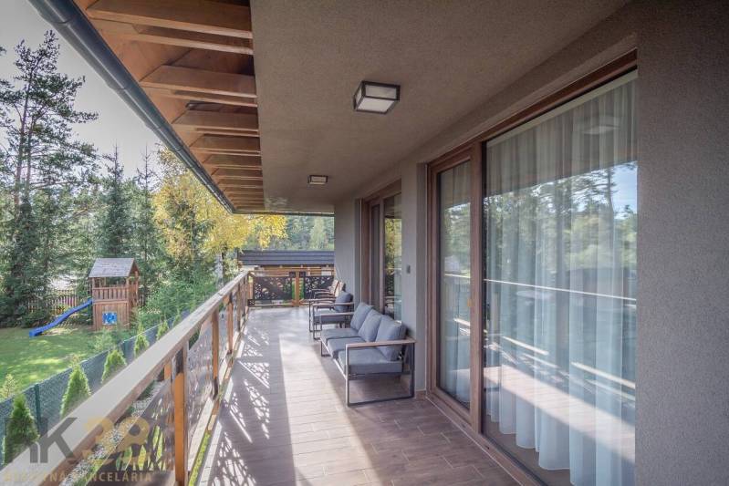 Der Balkon einer 2-Zimmer-Wohnung in Tatranská Lomnica mit einem Boden in Holzoptik und Blick ins Grüne.