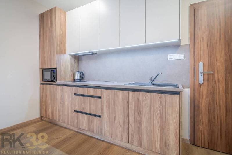 Küchenzeile mit Holzdekor, Einbaugeräte und Boden mit Holzdekor in einer 2-Zimmer-Wohnung.