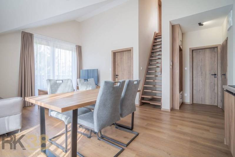 Wohnzimmer mit Esstisch und Treppe in einer 2-Zimmer-Wohnung, Boden mit Holzdekor.