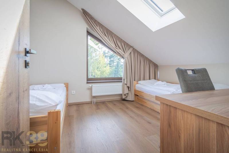 Schlafzimmer in einer 2-Zimmer-Wohnung mit zwei Betten und einem Boden in Holzoptik.