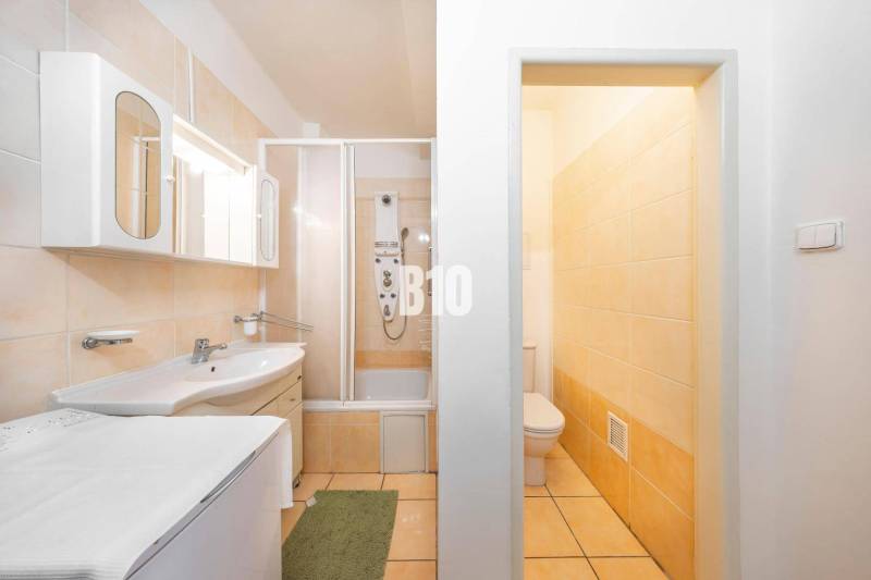 Badezimmer in einer 4-Zimmer-Wohnung mit Badewanne, Schränken und Toilette, in hellen Farben gehalten.