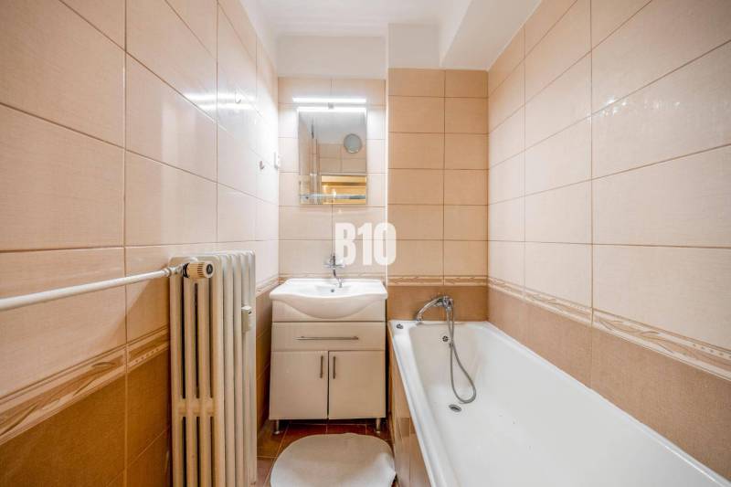 Badezimmer in einer 4-Zimmer-Wohnung mit Badewanne, hellen Fliesen und Heizkörper.