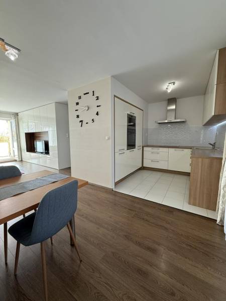 Essbereich in einer 4-Zimmer-Wohnung mit Holzboden und Küche im Hintergrund.