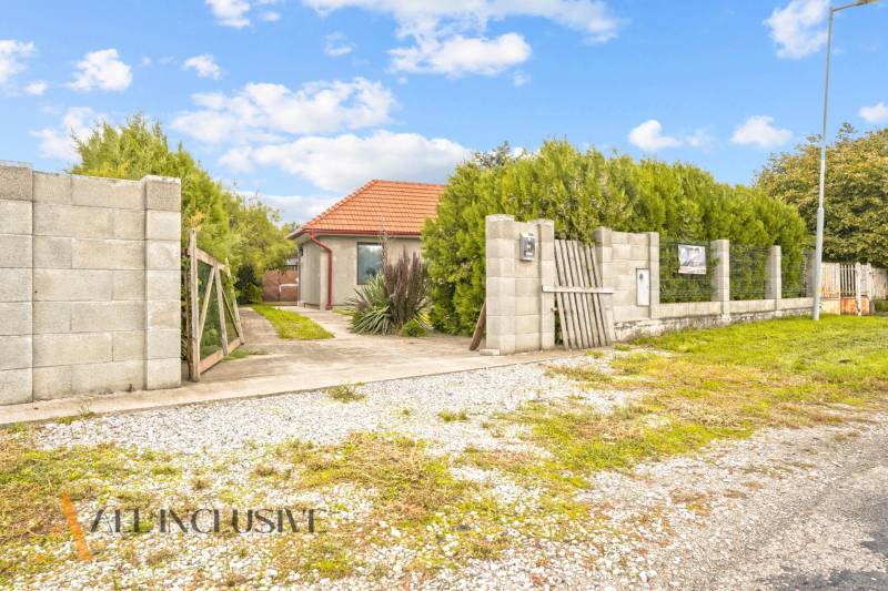 Ein Einfamilienhaus in Bátorové Kosihy, umgeben von Grün, mit einem Weg, der zum Tor führt.