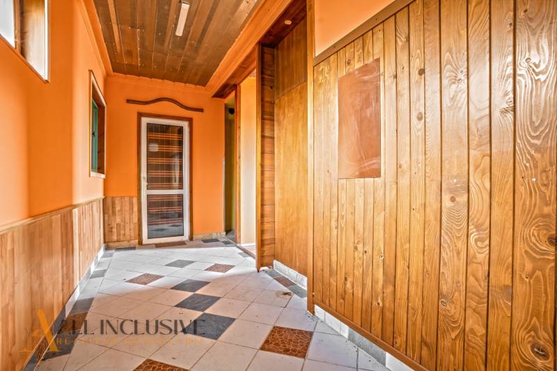 Ein Flur in einem Einfamilienhaus mit Holzverkleidung und Fliesenboden.