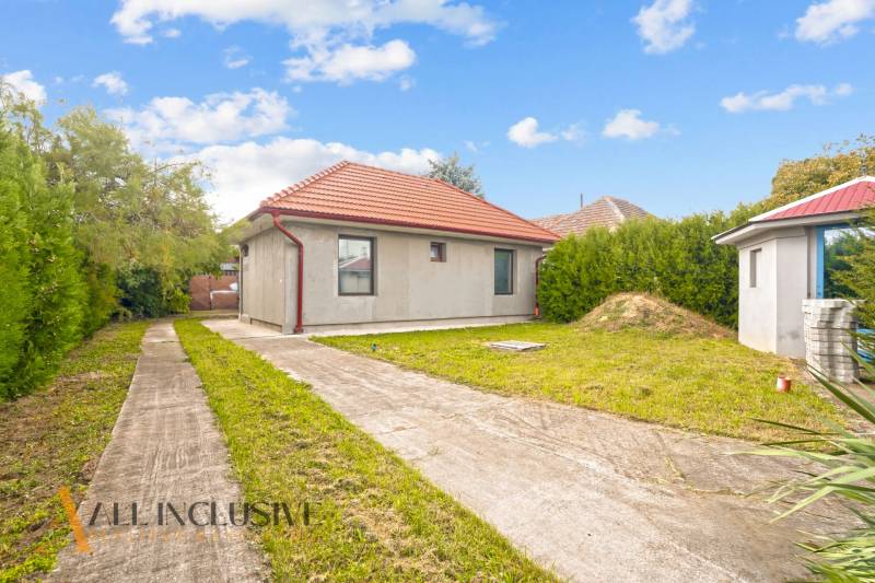 Ein Einfamilienhaus in Bátorove Kosihy, mit Rasen, Betonweg und rotem Dach.