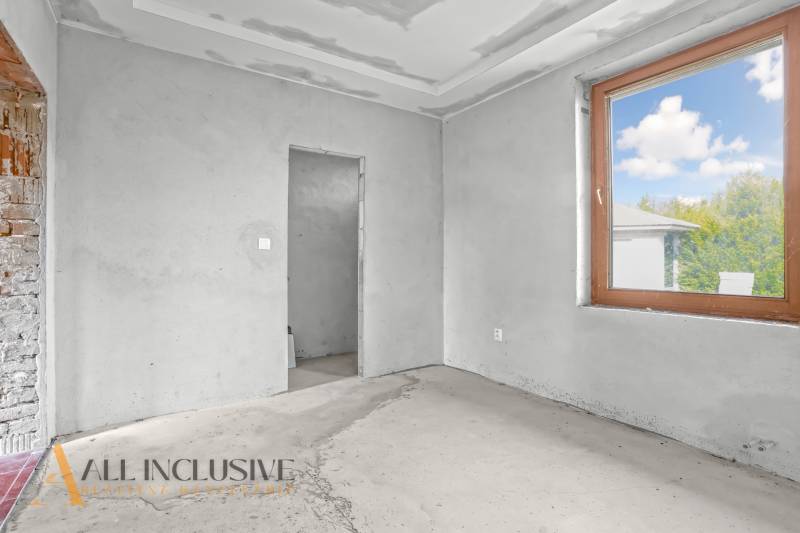 Innenraum eines Einfamilienhauses mit unvollendeten Wänden und großem Fenster.