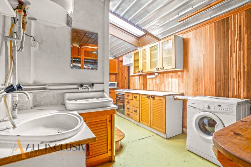 Küche in einem Einfamilienhaus mit Holzschränken, Spüle und Waschmaschine.