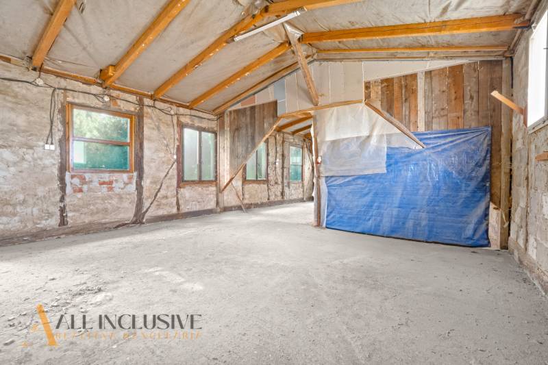 Innenraum eines Einfamilienhauses mit rohen Wänden und Holzbalken.