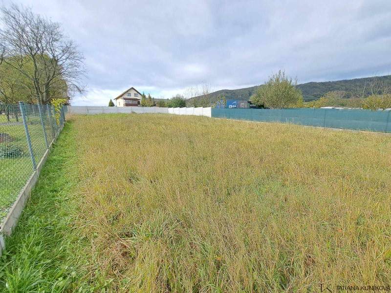 Grundstück mit Gras, Bäumen, geeignet zum Wohnen, eingezäunt, Haus im Hintergrund.