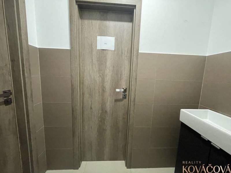 Innenraum von Geschäftsräumen mit WC-Türen, verkleidete Wände, Keramikwaschbecken.