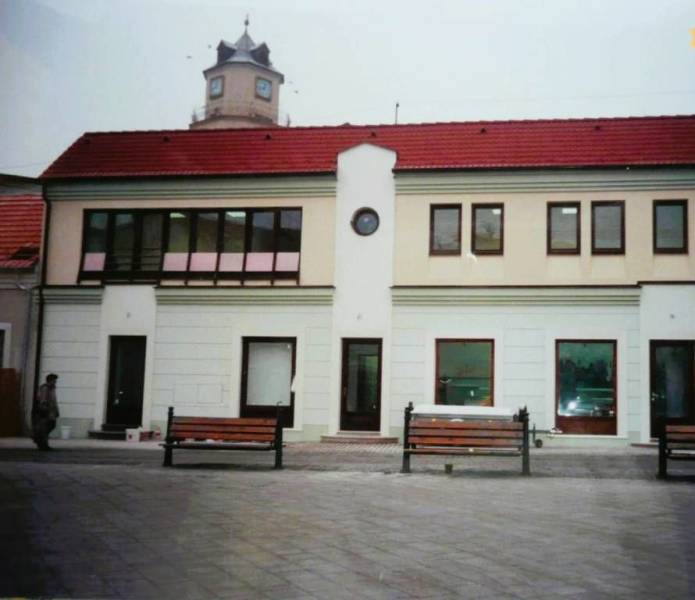 Geschäftsräume am Štúrovo námestie in Trenčín mit einem Turm im Hintergrund.