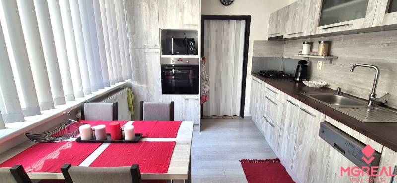 Küche mit Esstisch, weißen Jalousien und Küchenzeile in einer 2-Zimmer-Wohnung.