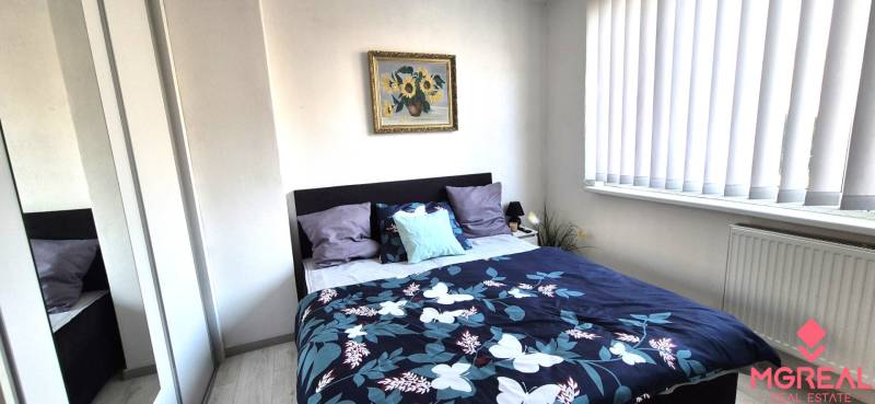 Schlafzimmer in einer 2-Zimmer-Wohnung mit Bett, Bild und Spiegelschrank.