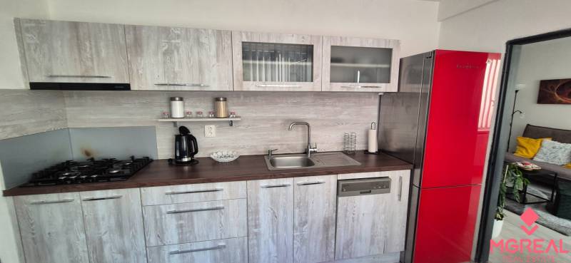 Küche in einer 2-Zimmer-Wohnung mit einem roten Kühlschrank und einem Boden in Holzoptik.