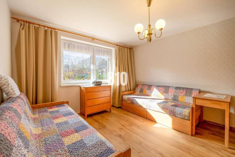 Ein Zimmer in einem Einfamilienhaus mit Betten, Holzelementen und bunten Decken.