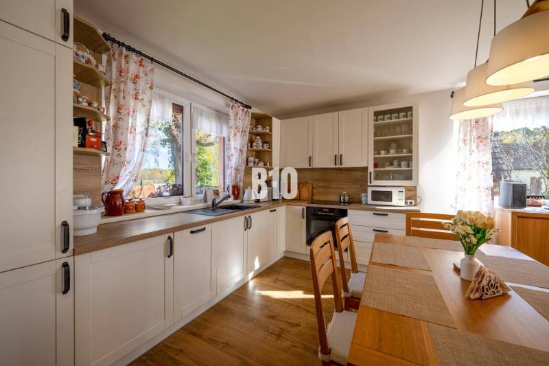 Eine Küche in einem Einfamilienhaus mit einem Boden in Holzoptik und hellen Möbeln.